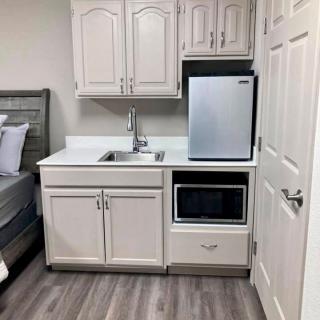 A compact kitchenette with a sink, microwave, and mini fridge adjacent to a bedroom.