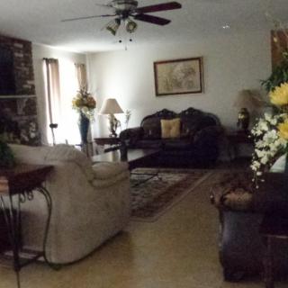 A cozy living room with comfortable sofas, a decorative carpet, and floral arrangements.