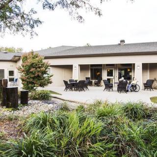 A cozy outdoor patio area with tables and chairs, surrounded by lush greenery.