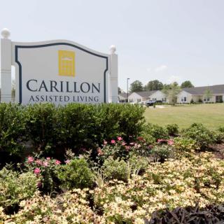 A sign for Carillon Assisted Living surrounded by a landscaped garden.