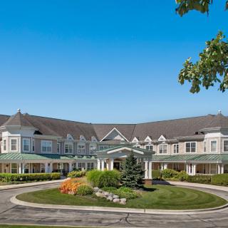 A large residential building with a circular driveway and landscaped front yard.