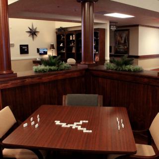A cozy game room with a table set up for dominoes, surrounded by chairs and wooden paneling.