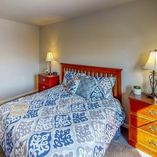 A cozy bedroom with a patterned bedspread, wooden furniture, and soft lighting.