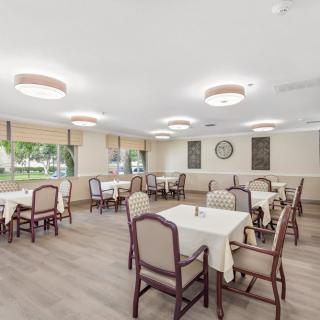 A spacious dining room with neatly arranged tables and chairs, featuring bright lighting and large windows.