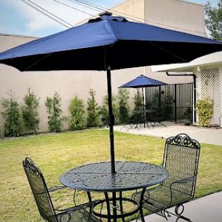 A cozy outdoor seating area with a table and chairs under a navy blue umbrella.