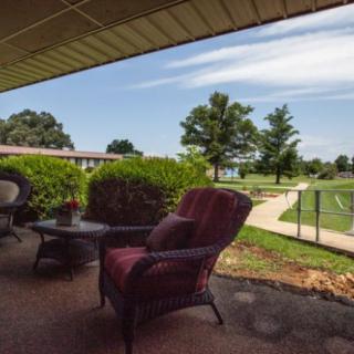 A cozy patio area with outdoor furniture overlooks a lush garden and winding pathway.