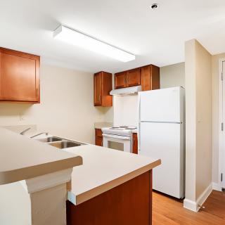 A small kitchen with wooden cabinetry, a white refrigerator, and a stove.