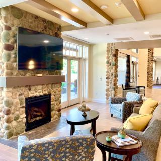 A cozy and modern living room featuring a stone fireplace and ample natural light.