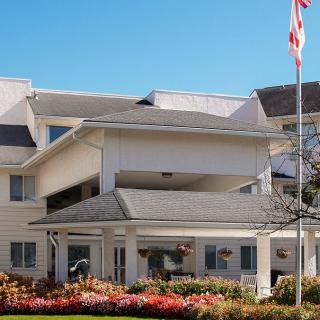 A well-maintained residential building with an American flag and landscaped garden.