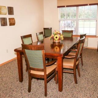 A neatly arranged dining room with a wooden table and eight chairs, accented with a floral centerpiece.