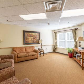 A cozy living room with sofas, lamps, and a large window providing natural light.