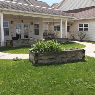 A residential home with a porch and garden bed in the yard.