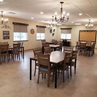 A spacious dining room with multiple tables and chairs, adorned with chandeliers.