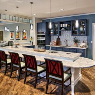 A modern kitchen with a large island featuring bar stools and pendant lighting, complemented by stylish blue cabinets.