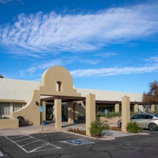 A southwestern-style building with a parking lot under a blue sky.