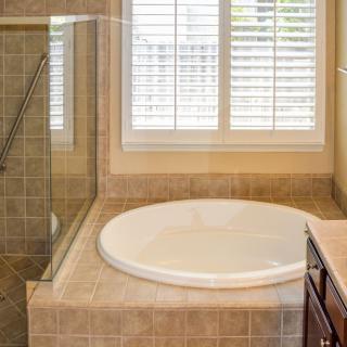 A modern bathroom with a round bathtub and tiled walls.