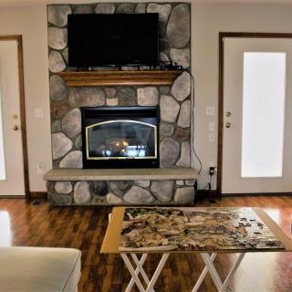A cozy living room with a stone fireplace and a puzzle on the table.