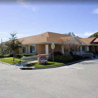 A one-story building with a parking lot, surrounded by trees under a clear blue sky.
