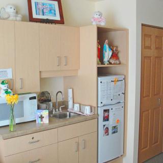 A small kitchen area with wooden cabinets, a microwave, a fridge, and decorative items.