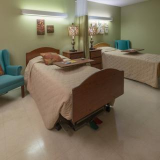 A cozy bedroom featuring two beds, a comfortable armchair, and decorative elements.