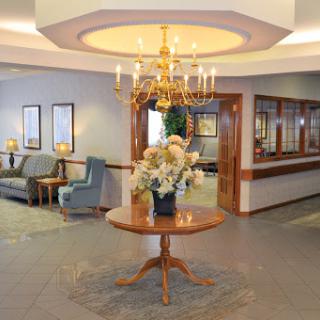 A beautifully decorated lobby featuring elegant furniture and floral arrangements under a chandelier.