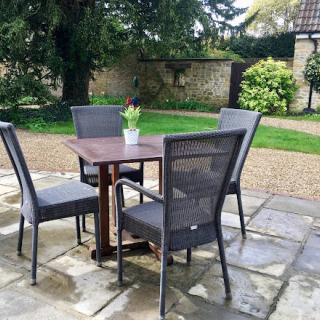 A cozy outdoor seating area with a table and chairs, set in a green garden.