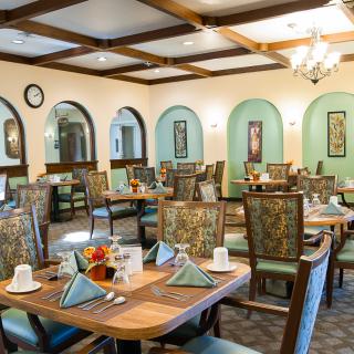 A cozy restaurant dining room with neatly arranged tables and chairs, complete with elegant decor and lighting.