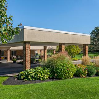 A modern building set in a lush green landscape with trees and well-maintained gardens.