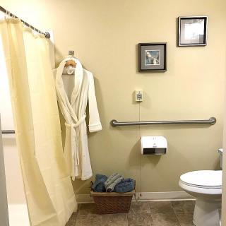 A well-organized bathroom with a shower, robe, and towels.