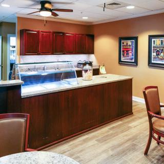 A cozy coffee shop interior featuring a wooden counter and seating area with art pieces on the walls.