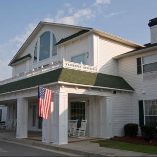 A white house with a green roof and an American flag displayed at the entrance.