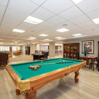A spacious game room featuring a green felt pool table and inviting seating arrangements.