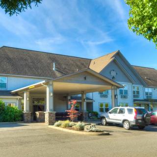 A hotel entrance with parked cars and a clear blue sky.