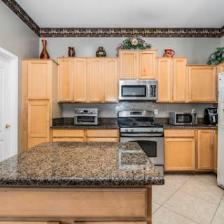 A modern kitchen featuring wooden cabinets, granite countertops, and stainless steel appliances.
