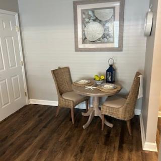 A cozy dining area featuring a small round table with two chairs, adorned with simple decor and artwork on the wall.