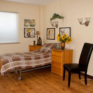 A cozy bedroom featuring a plaid bedspread, wooden furniture, and cheerful floral decor.