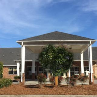 A well-maintained building entrance with a landscaped garden and clear blue sky.