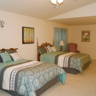 A cozy bedroom with two neatly made beds featuring matching bedding and decor.
