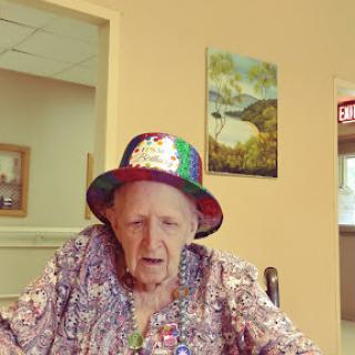 An elderly woman wearing a colorful hat, enjoying her time indoors.