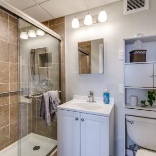 Modern bathroom with glass shower, vanity sink, and overhead lighting.