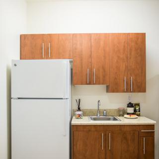 A compact kitchen with wooden cabinets, a white refrigerator, and a small sink area.