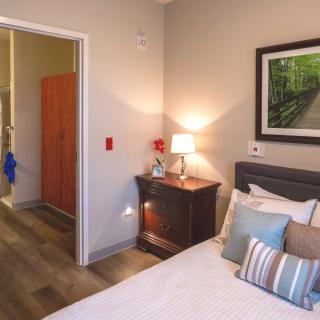 Cozy bedroom with a neatly made bed, side table lamp, and wall art.