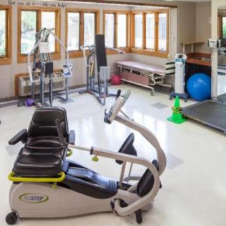 A well-equipped rehabilitation room with various exercise machines and therapy tools.