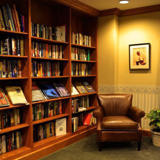 A cozy reading corner with a leather armchair and a bookshelf filled with books.