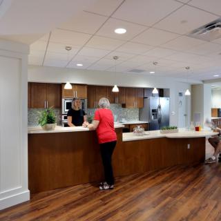 A modern kitchen with wooden cabinets and people interacting at a counter.