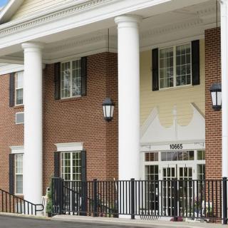 The image shows a brick building with white columns and multiple windows at the entrance.