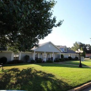 A suburban house with a well-maintained lawn and surrounding trees on a sunny day.