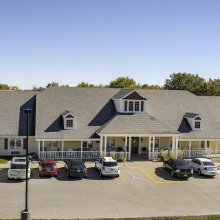 A building with a parking lot and several cars parked in front under a clear blue sky.