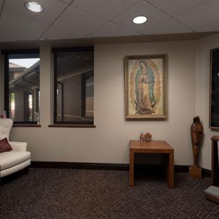 A cozy room featuring a white couch, religious artwork on the wall, and warm lighting.