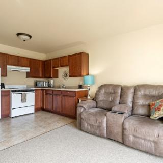A cozy open-concept living area featuring a kitchen with wooden cabinets and a comfortable recliner sofa.